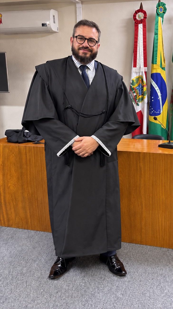 Pablo Dietrich de beca em sala de sessões do Tribunal de Justiça de Santa Catarina, diante das bandeiras do Brasil e de Santa Catarina